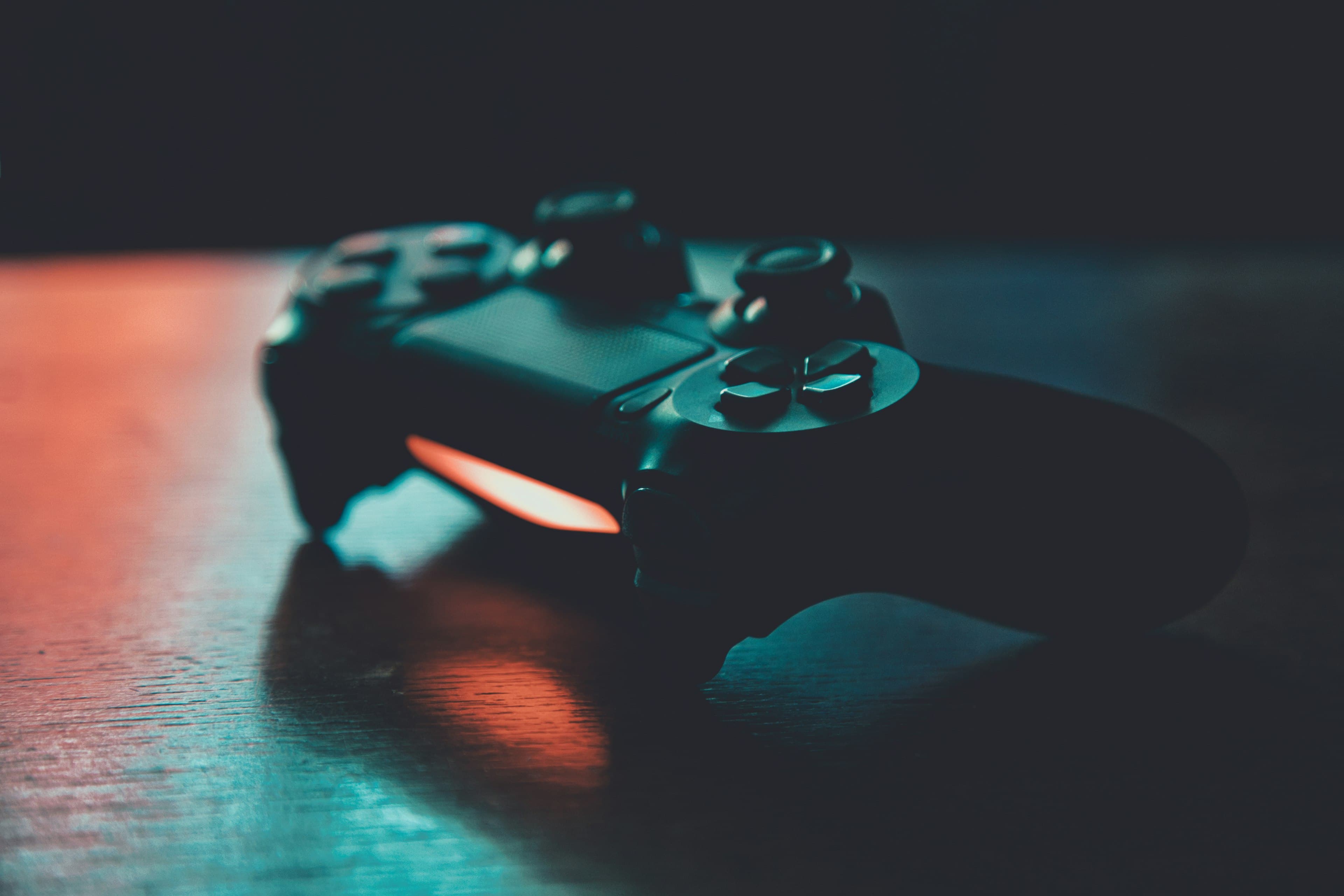 Game controller lit by teal and orange neon light on a dark table